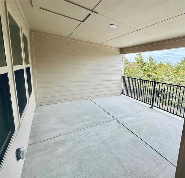 Covered patio featuring concrete flooring and a black metal railing