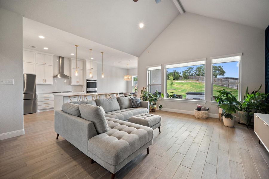 Living room with light wood-type flooring, high vaulted ceiling, recessed lighting, beamed ceiling, and ceiling fan