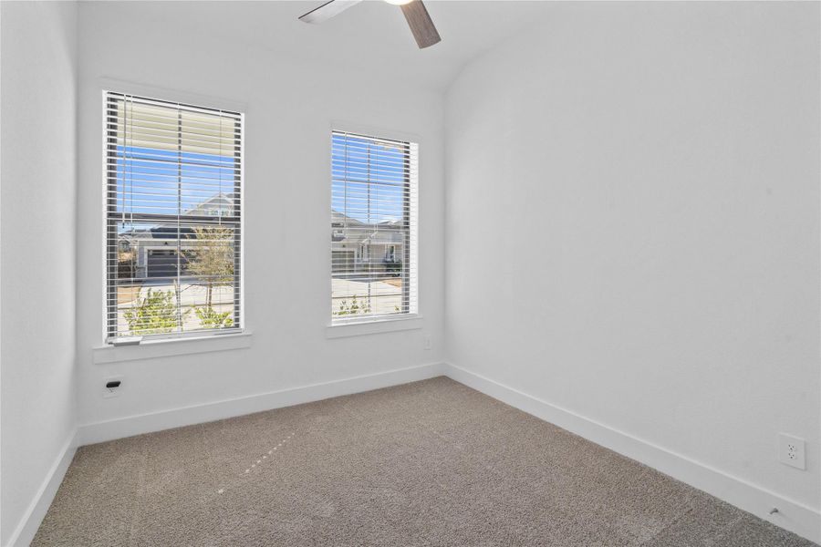 Tucked peacefully in the front of the home is this secondary bedroom. It features high sloped ceiling, ceiling fan, custom paint, plush carpet, large windows with fitted blinds, and an ample sized closet space!