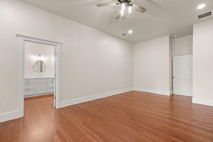 Rich hardwood floors create a warm foundation in this spacious bedroom, leading to a well-appointed primary bathroom. Rich hardwood floors create a warm foundation in this spacious bedroom, leading to a well-appointed primary bathroom.