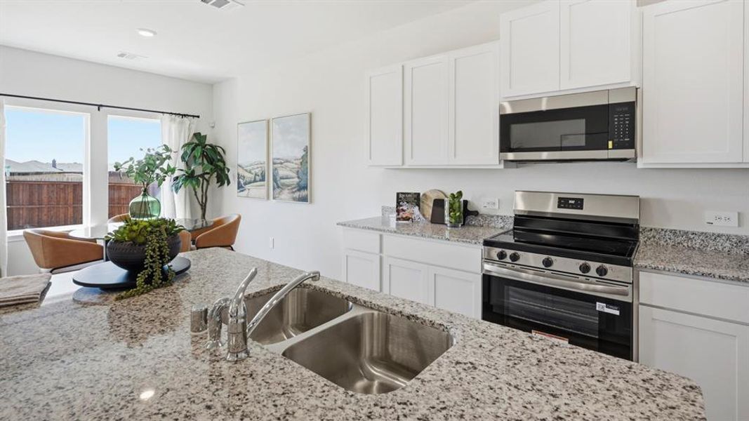 Kitchen featuring stainless steel appliances, white cabinets, light stone countertops, and recessed lighting Kitchen featuring stainless steel appliances, white cabinets, light stone countertops, and recessed lighting