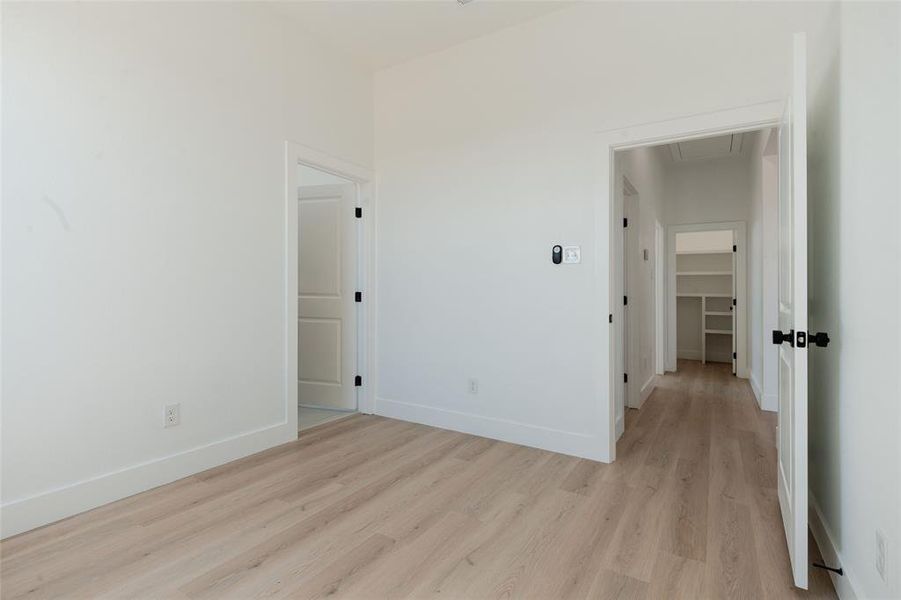 Secondary bedroom with light wood-style flooring and a walk in closet