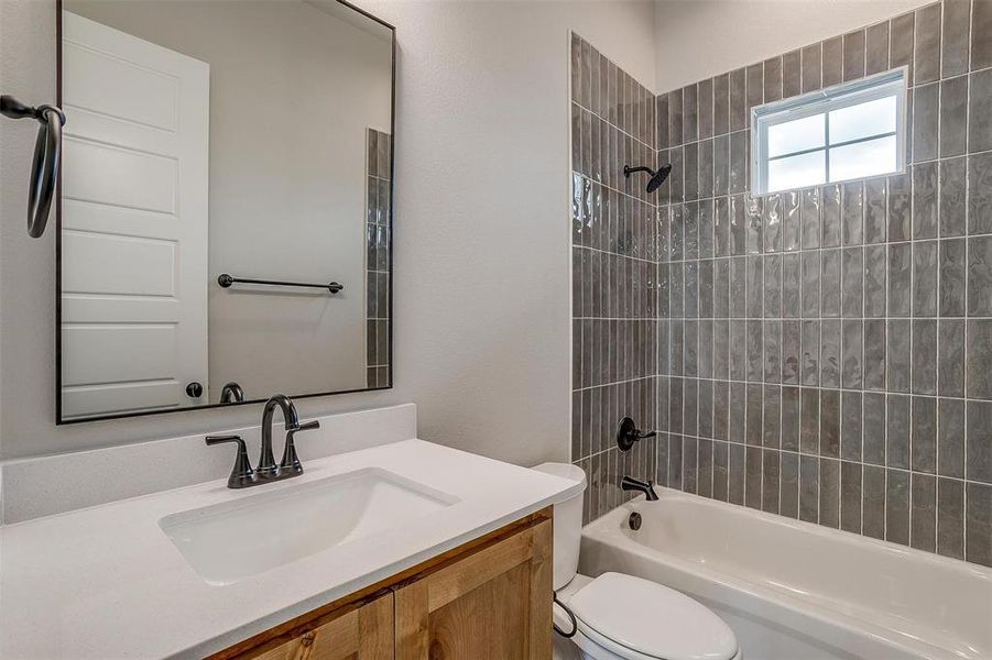 Full bathroom with tiled shower / bath, vanity, and toilet