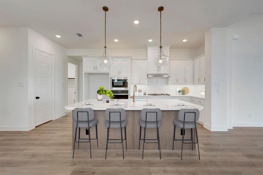 Two tone kitchen featuring light wood-type flooring, a kitchen breakfast bar, pendant lighting, a center island with sink, and stainless steel appliances Two tone kitchen featuring light wood-type flooring, a kitchen breakfast bar, pendant lighting, a center island with sink, and stainless steel appliances