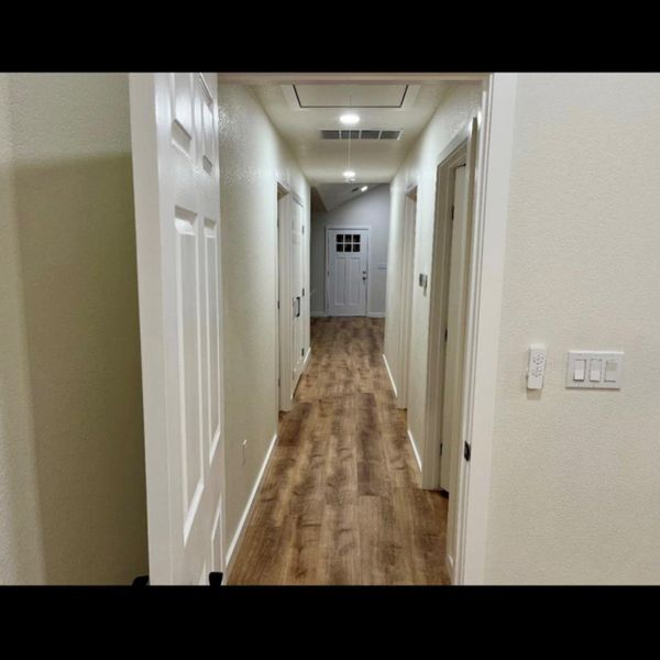 A well-lit corridor welcomes you home, featuring warm wood flooring and recessed lighting.