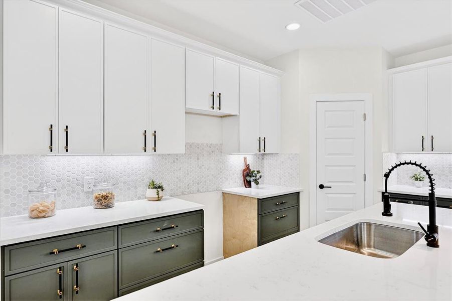 Contemporary kitchen featuring white upper cabinetry and contrasting green lower cabinetry with dark hardware