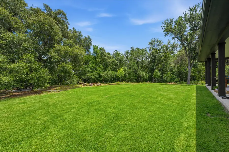 A spacious backyard with mature trees bordering a verdant lawn. A spacious backyard with mature trees bordering a verdant lawn.