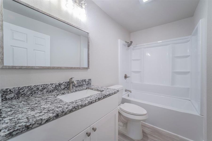 Full bathroom with shower / washtub combination, vanity, toilet, and hardwood / wood-style floors