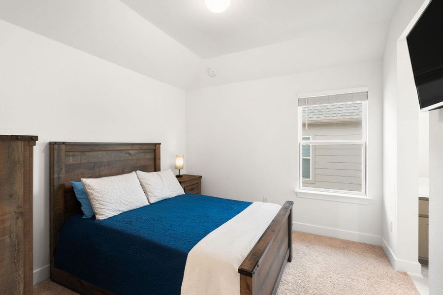 A cozy bedroom with a vaulted ceiling and a window offering natural light.