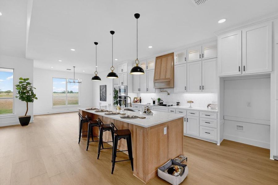 Kitchen with light wood-style floors, decorative backsplash, white cabinets, recessed lighting, and a breakfast bar