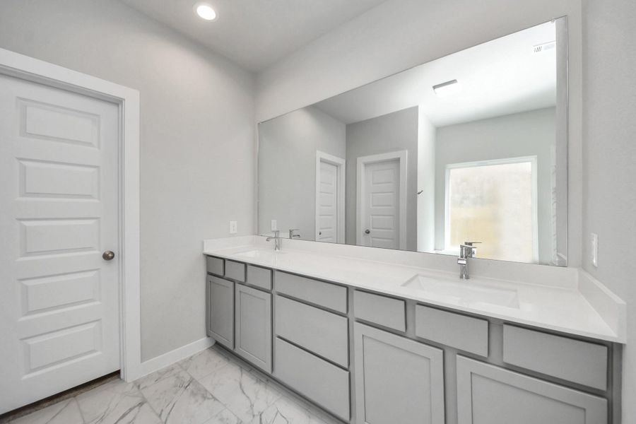Elevate your daily routine at the elegant vanity, now equipped with double sinks, light countertops, modern hardware, and beautiful recessed lights. Sample photo of completed home with similar floor plan. Actual colors and selections may vary.