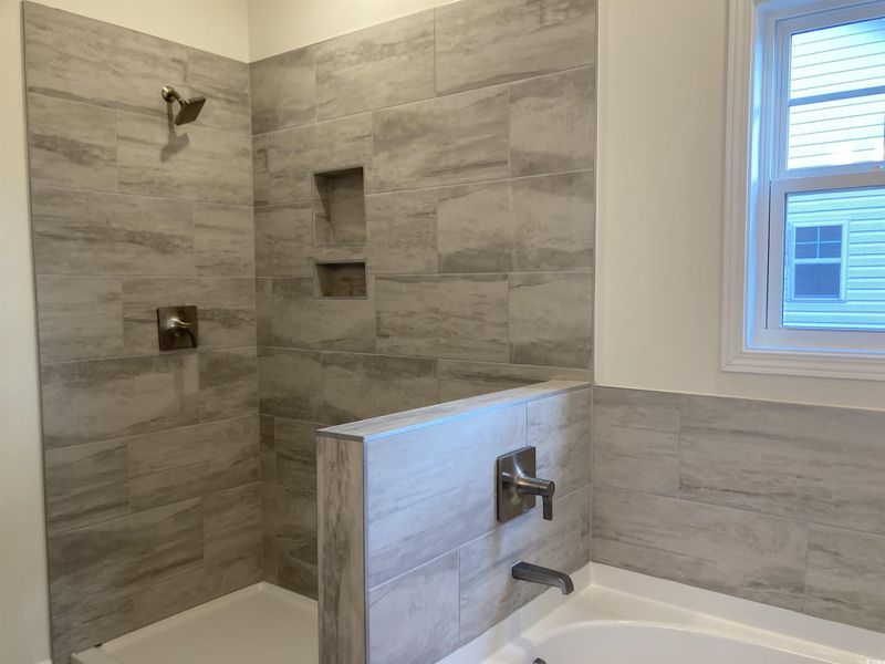 Full bathroom featuring a bath and a tile shower