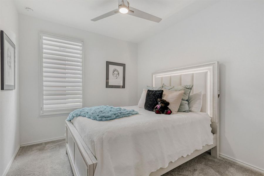 Carpeted bedroom with a ceiling fan and baseboards