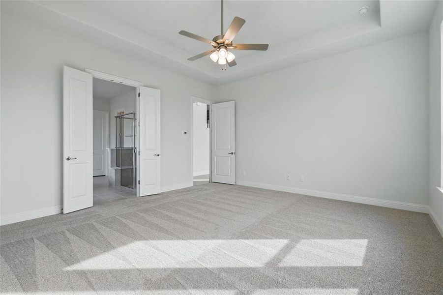 Unfurnished bedroom featuring a raised ceiling, baseboards, carpet, and a ceiling fan Unfurnished bedroom featuring a raised ceiling, baseboards, carpet, and a ceiling fan