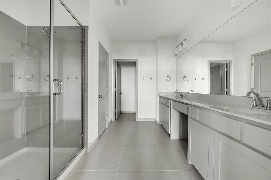 Bathroom featuring a stall shower, double vanity, and light tile patterned floors Bathroom featuring a stall shower, double vanity, and light tile patterned floors