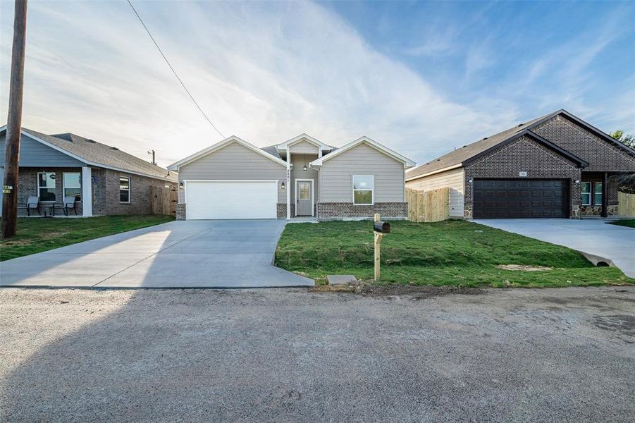 View of front of property featuring a garage and a front lawn