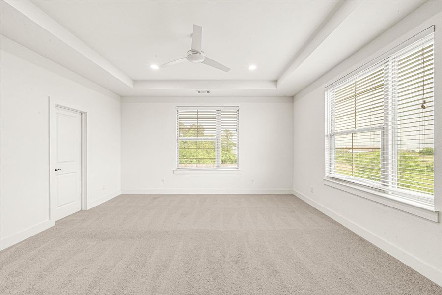 This stunning primary suite offers a spacious layout, modern tray ceilings, and abundant natural lighting. Spacious
