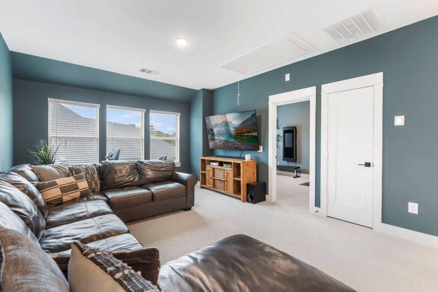 This cozy living room features a spacious sectional sofa, a wall-mounted TV, and large windows for ample natural light. The teal walls and white trim create a modern, inviting atmosphere. This cozy living room features a spacious sectional sofa, a wall-mounted TV, and large windows for ample natural light. The teal walls and white trim create a modern, inviting atmosphere.