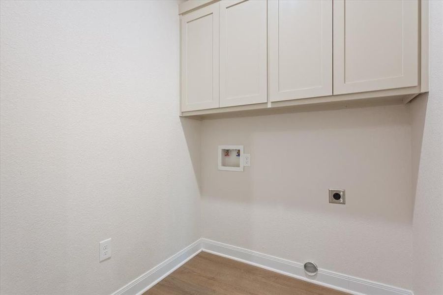 Laundry room with light wood finished floors, washer hookup, cabinet space, and electric dryer hookup