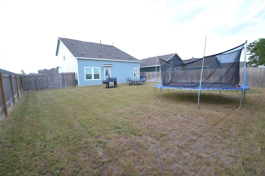 Fenced backyard with a trampoline and a patio