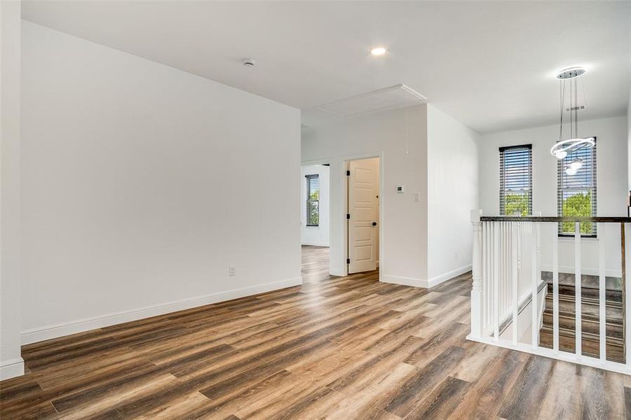 Unfurnished room with wood finished floors, attic access, and recessed lighting