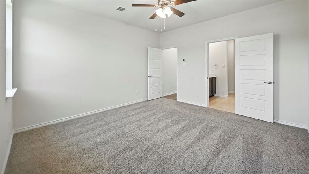 Unfurnished bedroom with light carpet, connected bathroom, and ceiling fan