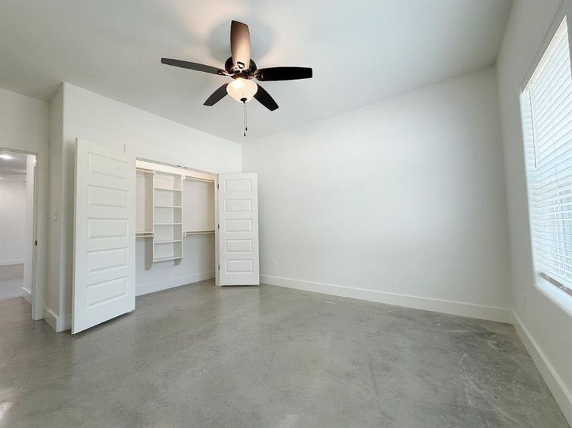 Unfurnished bedroom with finished concrete flooring and ceiling fan Unfurnished bedroom with finished concrete flooring and ceiling fan