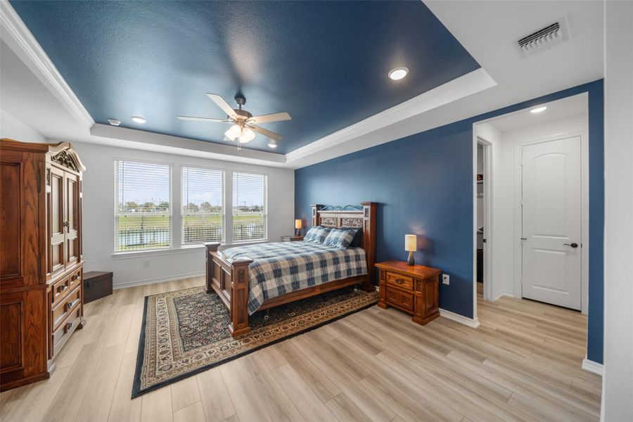 The primary bedroom has a tray ceiling, ceiling fan, recessed lighting, plenty of space for larger furniture or sitting space.