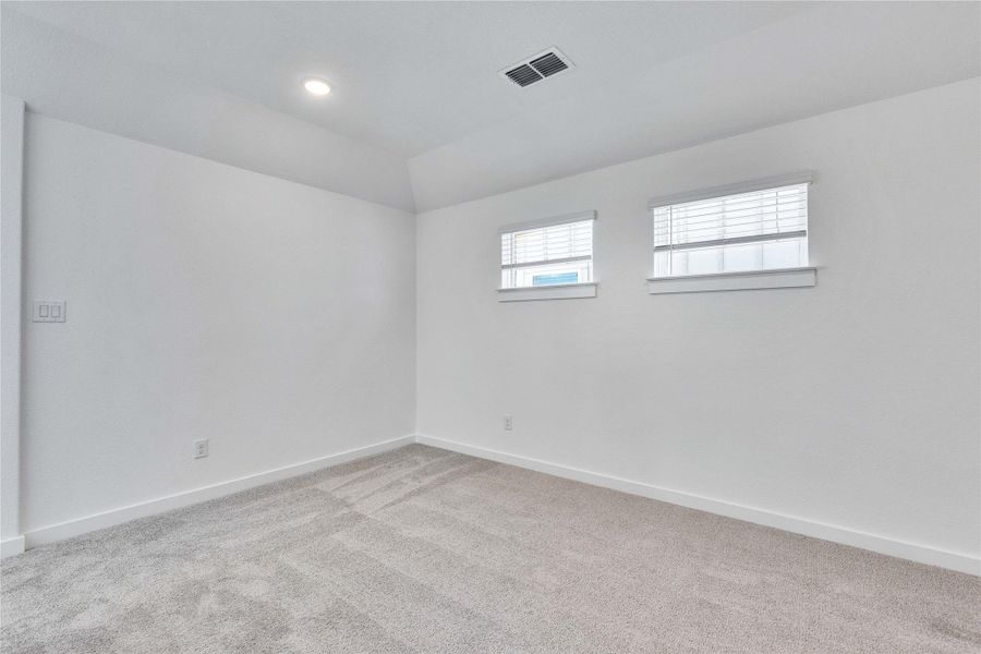 Carpeted empty room featuring vaulted ceiling and recessed lighting Carpeted empty room featuring vaulted ceiling and recessed lighting