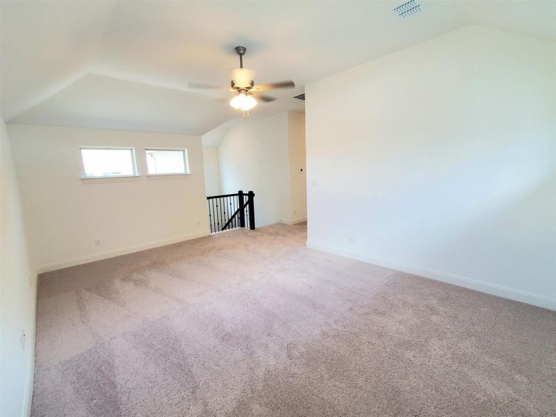 Additional living space with vaulted ceiling, ceiling fan, carpet flooring, and baseboards Additional living space with vaulted ceiling, ceiling fan, carpet flooring, and baseboards