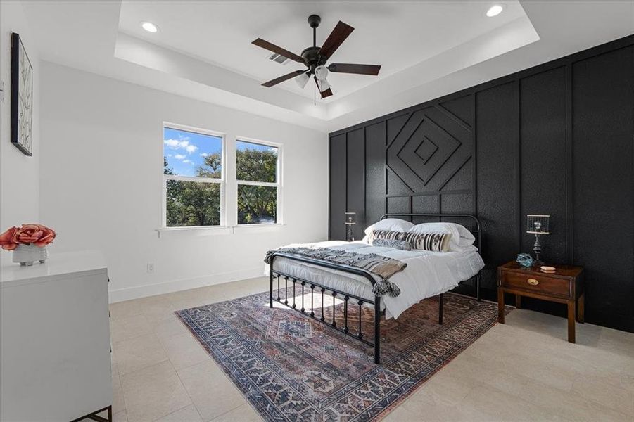 Primary Bedroom featuring a tray ceiling, accent wall