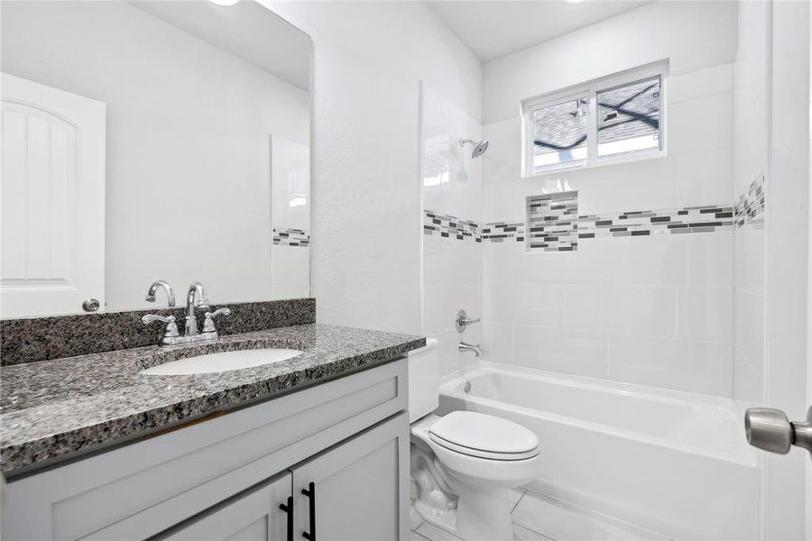 Full bathroom featuring vanity, toilet, and tiled shower / bath