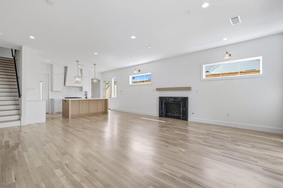 Unfurnished living room featuring stairs, recessed lighting, light wood-style flooring, and a fireplace Unfurnished living room featuring stairs, recessed lighting, light wood-style flooring, and a fireplace