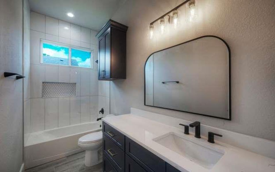 A well-appointed bathroom with a sleek vanity and tiled tub-shower combination.