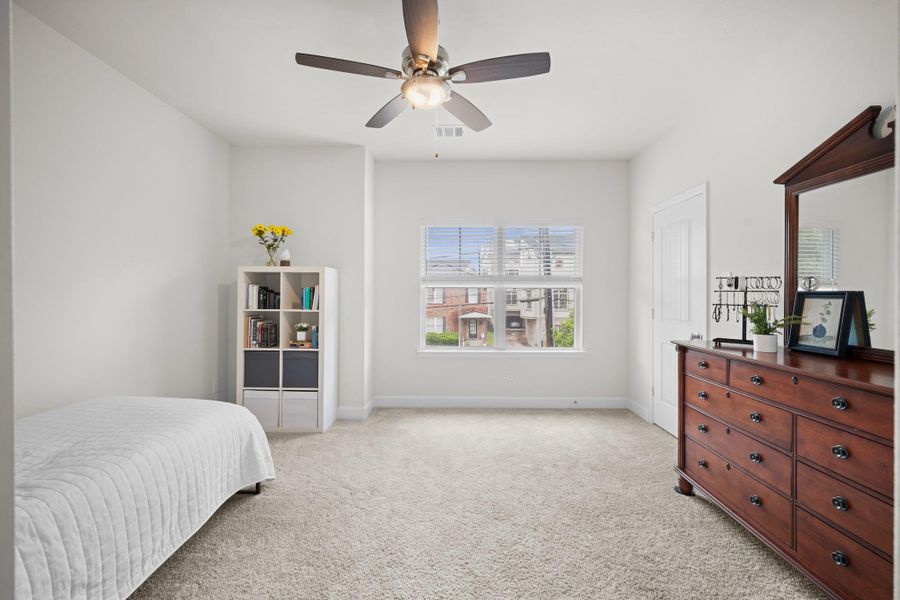 The front secondary bedroom on the second floor has a front-facing window, plush carpet, and a ceiling fan — a comfortable, well-proportioned room with good natural light. The front secondary bedroom on the second floor has a front-facing window, plush carpet, and a ceiling fan — a comfortable, well-proportioned room with good natural light.