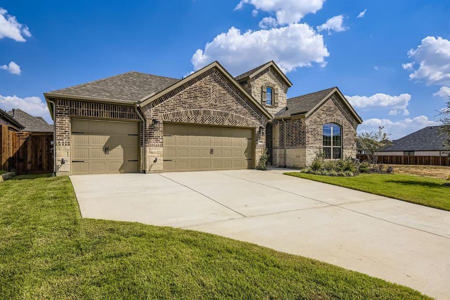 French country inspired facade with brick siding, a shingled roof, a garage, and concrete driveway