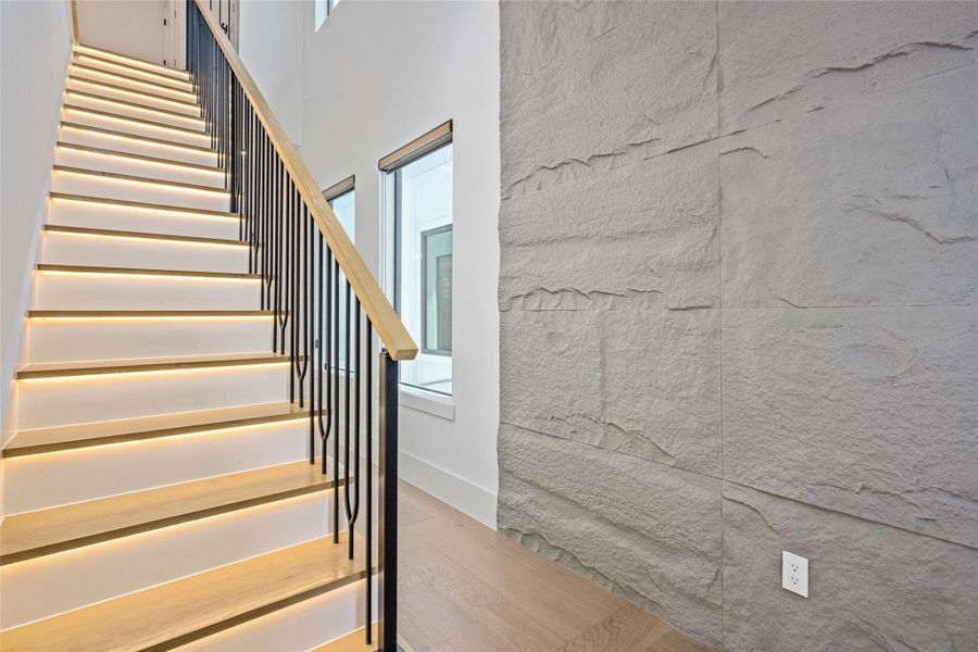 An exquisite white oak tread staircase with modern wrought iron railings and ambient under-stair lighting sets the tone for refined living.