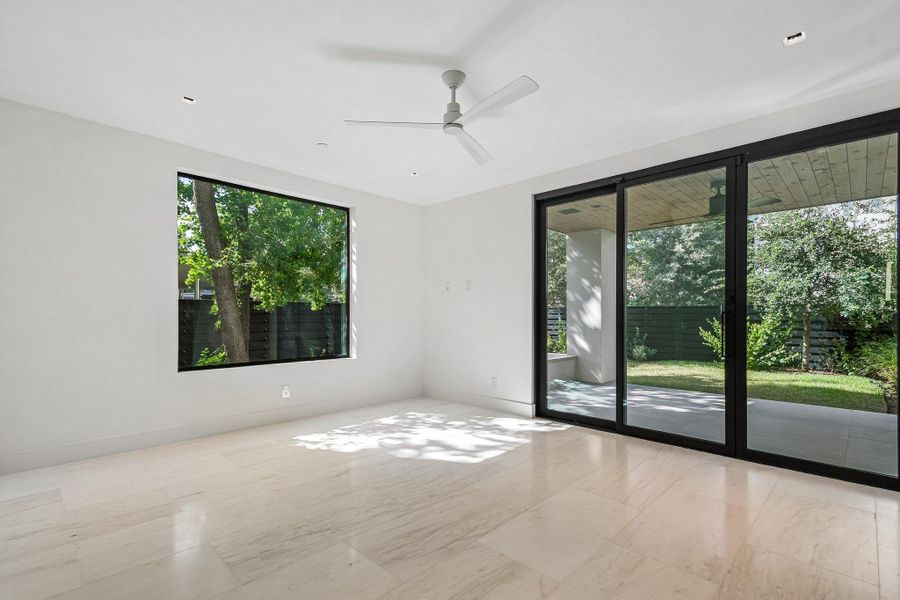 Gleaming stone tile floors pair with glass doors opening directly to the private yard. Gleaming stone tile floors pair with glass doors opening directly to the private yard.