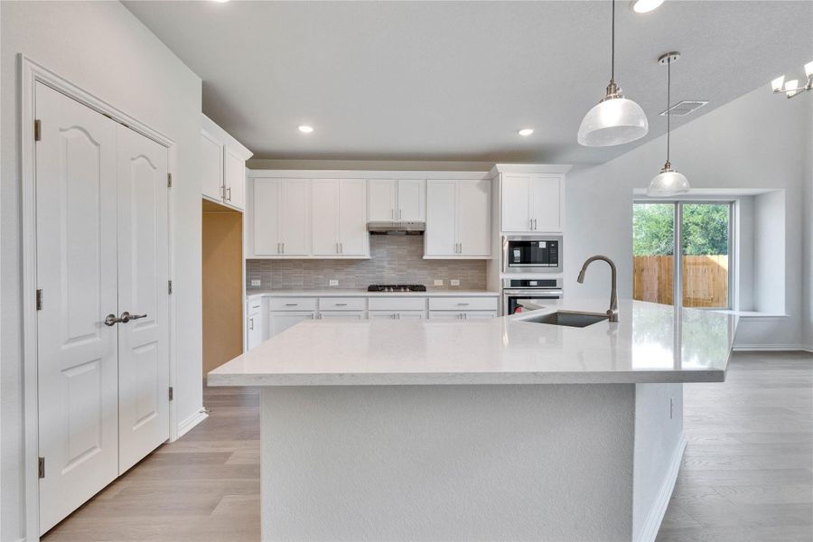 Kitchen with a sink, stainless steel appliances, light countertops, decorative backsplash, and white cabinetry Kitchen with a sink, stainless steel appliances, light countertops, decorative backsplash, and white cabinetry