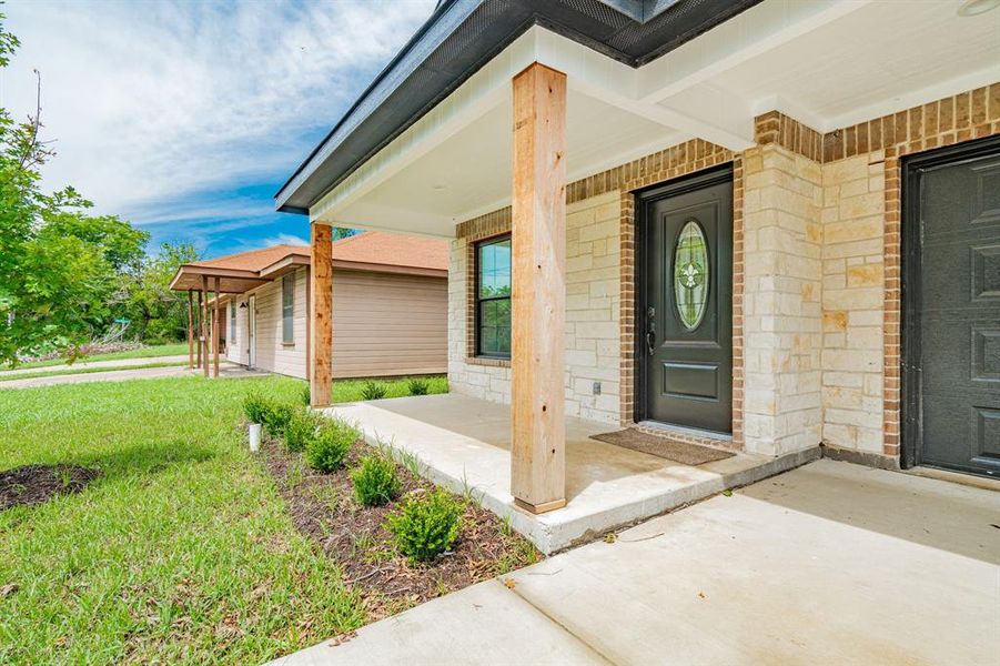 View of exterior entry featuring a porch and a yard