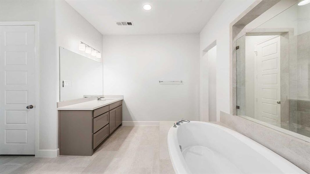 Bathroom with vanity, tile patterned flooring, and a bath