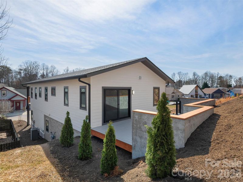 Rear exterior view showcasing the spacious rear deck with rear access, along with the home’s clean modern lines, cement HardiePlank siding, and low-maintenance setting.