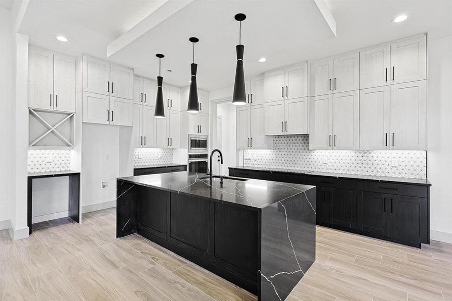 Kitchen with white cabinetry, sink, stainless steel appliances, pendant lighting, and a kitchen island with sink