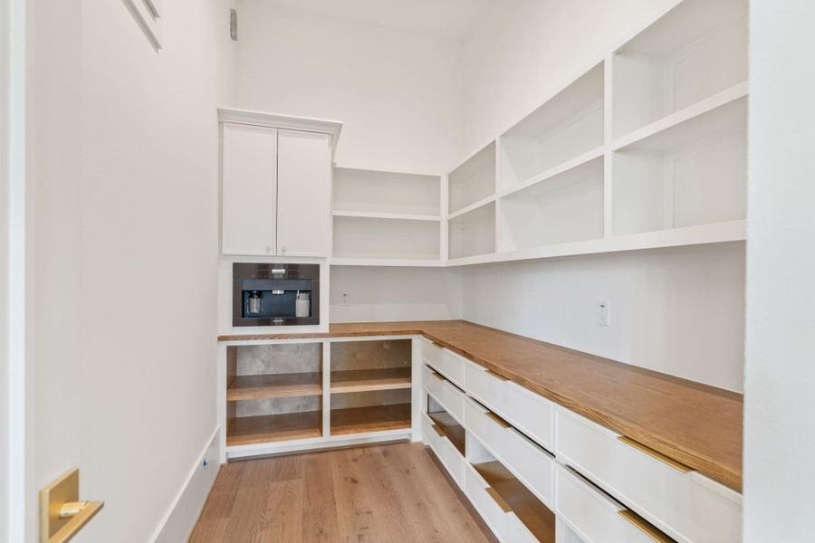 A dedicated prep space offers extensive counter surfaces, custom cabinetry, and open shelving for additional storage. Designed for convenience, this area supports effortless entertaining and organization