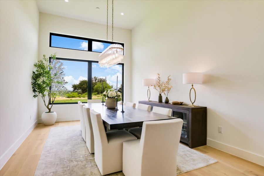 A spacious dining area features tall windows offering expansive views of the natural landscape.