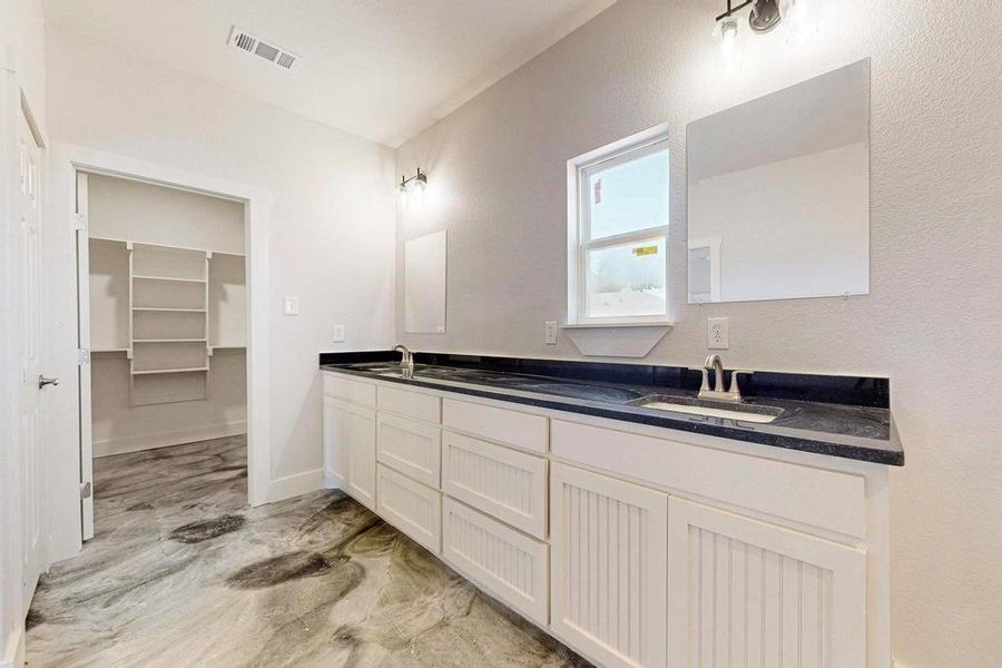 Bathroom with double vanity, a sink, visible vents, and baseboards