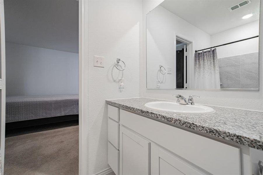 Full bath featuring light carpet, vanity, a shower with curtain, and connected bathroom