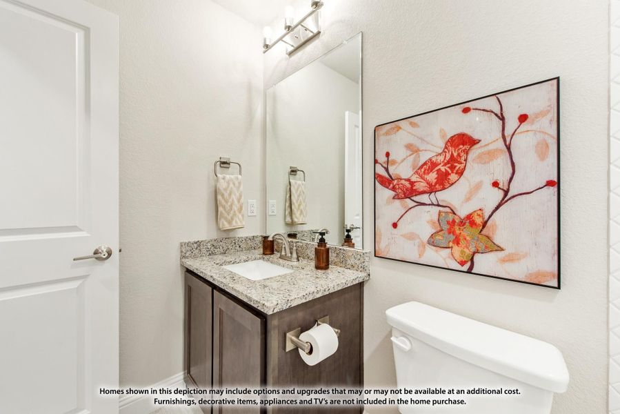 Half bathroom with dark wood vanity, granite countertop, large mirror, and decorative wall art Half bathroom with dark wood vanity, granite countertop, large mirror, and decorative wall art
