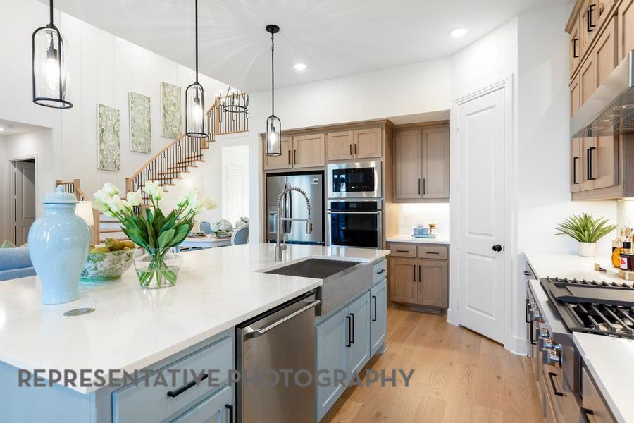 Kitchen with appliances with stainless steel finishes, light wood-style floors, light countertops, a spacious island, and recessed lighting Kitchen with appliances with stainless steel finishes, light wood-style floors, light countertops, a spacious island, and recessed lighting
