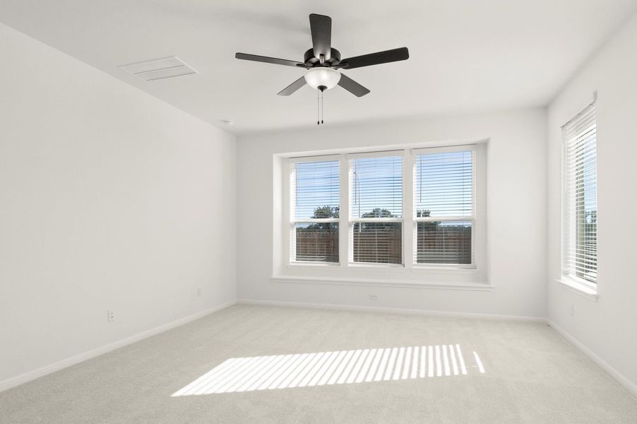 Carpeted spare room with a ceiling fan and baseboards